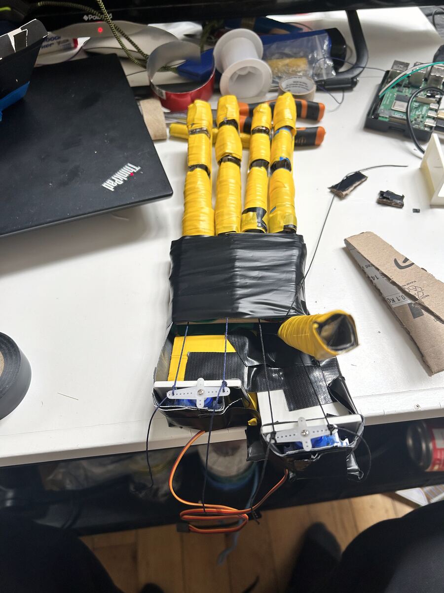 A DIY robotic hand built with duct tape, servos, and yellow electrical tape